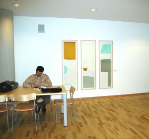 Man sitter vid bord framför konstverk på väggen